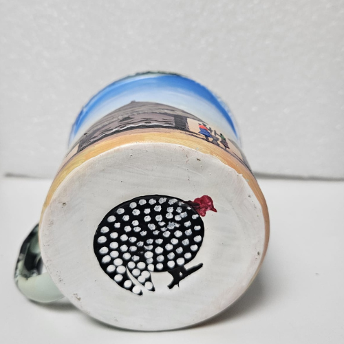 Tasse Kango – Scène de village à l’avant, pintade casquée en dessous